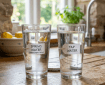 Two glasses of water labeled 'Spring Water' and 'Tap Water' on a wooden counter