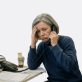 Stressed office worker holding a phone beside paperwork and computer